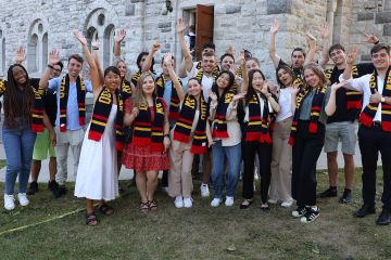 New first-year JD students donning their Queen’s Law scarves show their school spirit at their Orientation closing ceremony outside Grant Hall on September 6. (Photo by Bernard Clark)