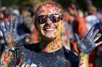 Queen's Student with Paint on face and hands smiling
