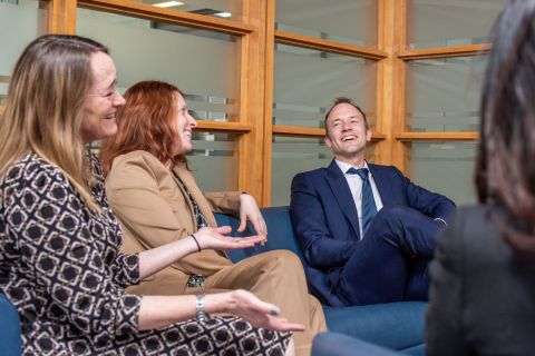 Four people converse in a meeting room