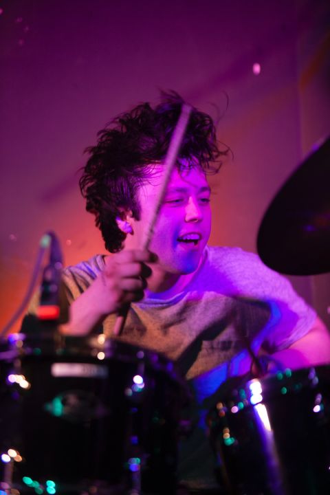 A young person plays drums