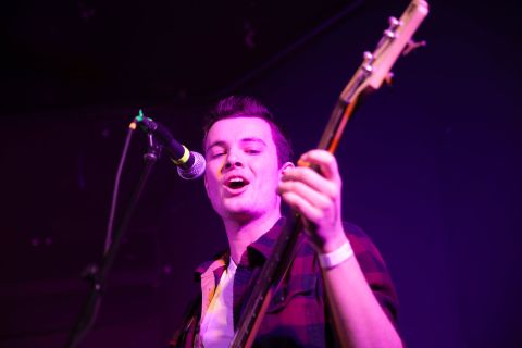 A young person plays a bass guitar and sings