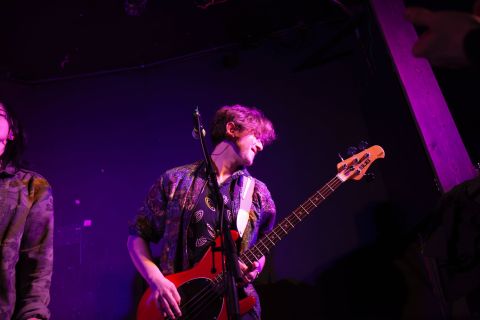 A young person plays a bass guitar