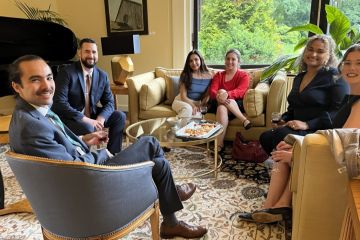 Students in formal wear, sitting & chatting around a table with snacks