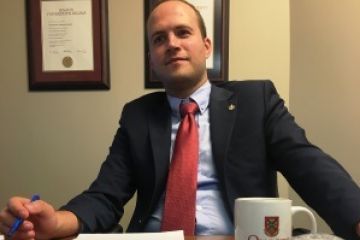 Nate Erskine-Smith, Law’10 (Arstci’07), sitting at his office desk, where his Dan Soberman Outstanding Young Alumni Award is proudly displayed