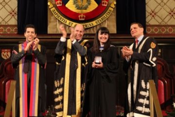 Photo by Bernard Clark. Convocation 2014: Emily Sherkey, Law’14, accepts the Medal in Law and is applauded by Rector Mike Young, Chancellor David Dodge and Principal Daniel Woof in Grant Hall.